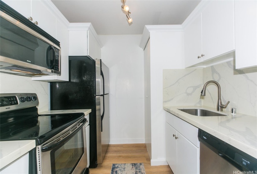 Kitchen with stone countertops and newer appliances (washer/dryer in closet near sink)