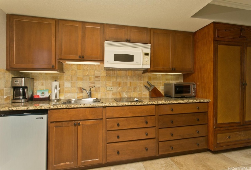 Kitchenette with 2-burner cooktop, microwave, toaster-oven, under-counter refrigerator.