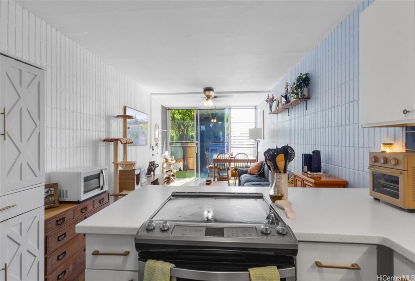 An updated kitchen includes a peninsula stone countertop, stainless steel appliances, and a modern blue, white, and brass color scheme that really pops!