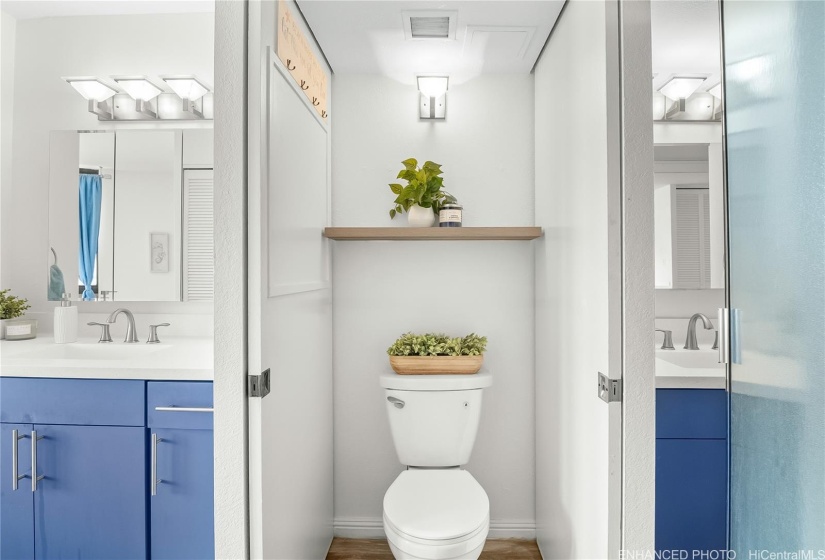 Digitally enhanced photo showcasing a rare Jack-and-Jill bathroom design. Positioned between the primary bedroom vanity (left) and the secondary bedroom vanity (right), the shared toilet area offers convenient, en-suite-style access from both bedrooms. For added privacy, the toilet can be closed off with pocket doors.