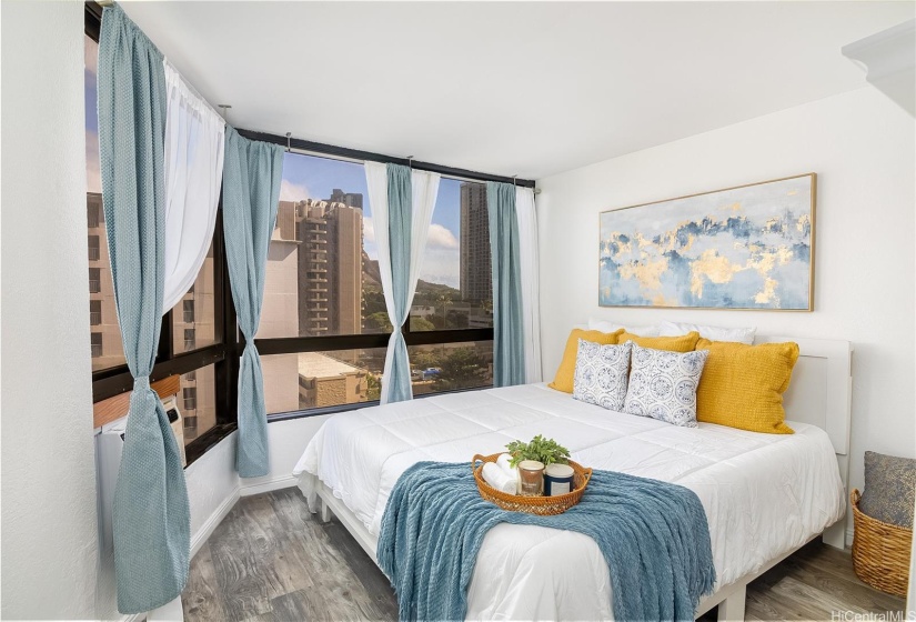 Primary bedroom bathed in natural sunlight, featuring a window AC unit to keep the space cool and comfortable year-round