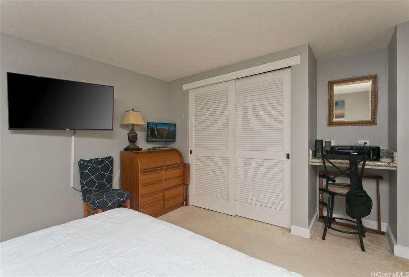 The bedroom features a mounted tv, a credenza and a built-in desk.