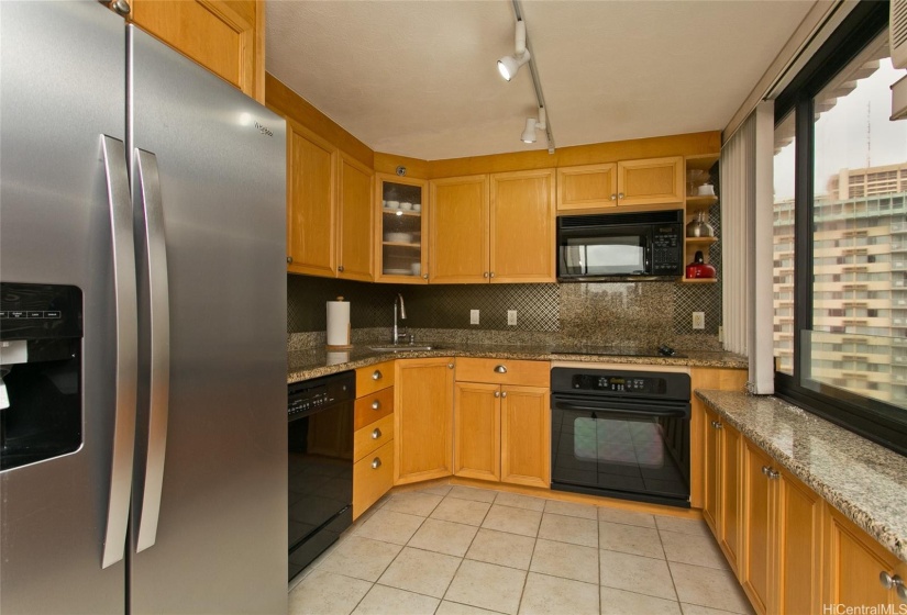 Kitchen features a newer stainless steel refrigerator and ceramic tile flooring. Lots of cabinet space!