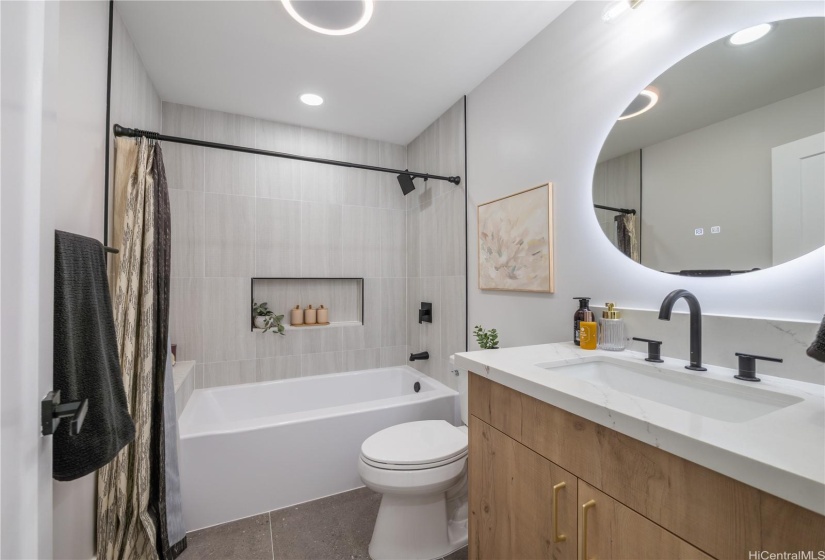 Hallway Full Bathroom has a luxe design aesthetic! Back-lit LED Mirrors, TechIncorporations that include Music Option and Vanity in Custom Oak Finish highlightthe Fingerling Neutral Tile Shower Tub Surround!