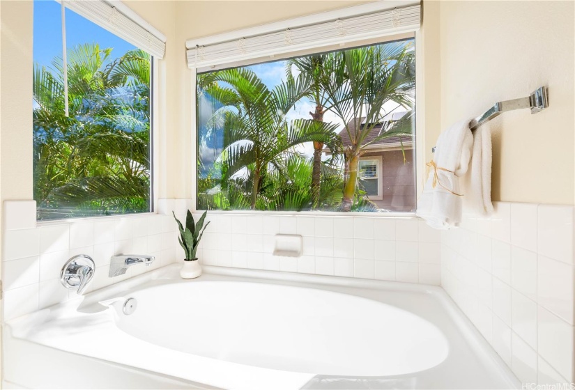 Soaking tub with a treetop view.