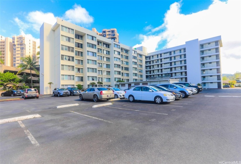 Another view of this well-equipped condo building, showcasing ample parking space along with access to a swimming pool and barbecue area for relaxation and entertainment. Ideal for residents seeking a blend of convenience and leisure amenities.