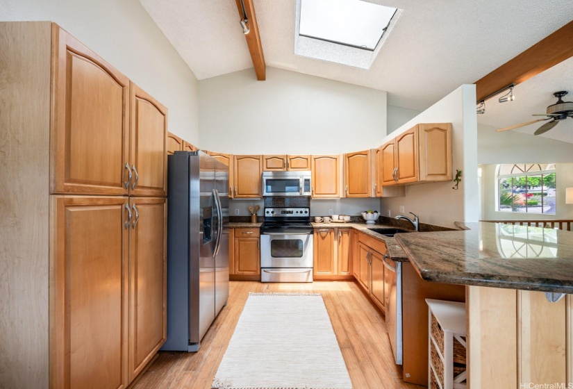 Kitchen has a skylight for natural light, and wooden cabinets and pantry.