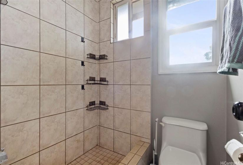 A large shower upgraded with tiles and multiple windows for proper ventilation.