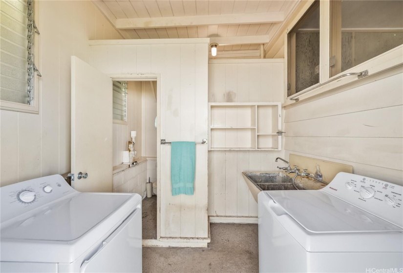 The enclosed laundry room has a new full sized washer and dryer along with a large double wash basin.