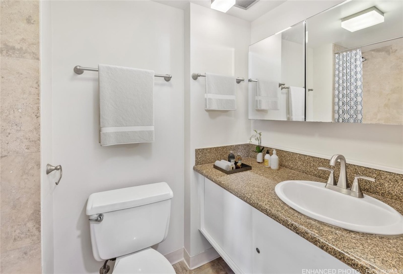 both bathrooms are en-suite with granite counter tops.  Primary bathroom has travertine shower stall. Enhanced photo. Virtual staging.