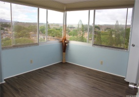Bedroom with large windows showing panoramic view of city and mountains.