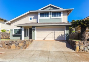 Front of home with two car garage and rock wall surrounding the entire property.