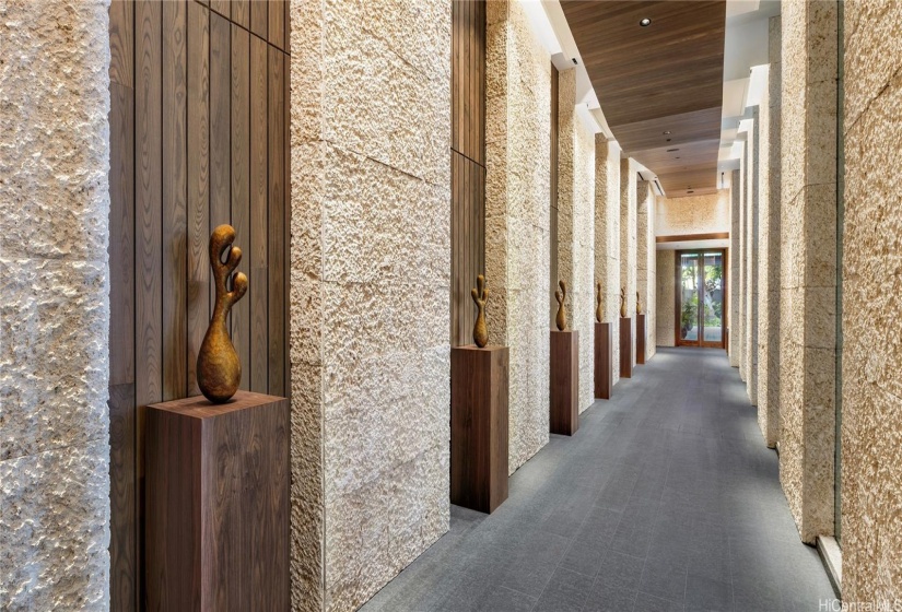 Museum like great-hall corridor lined with coral walls leading to the elevators