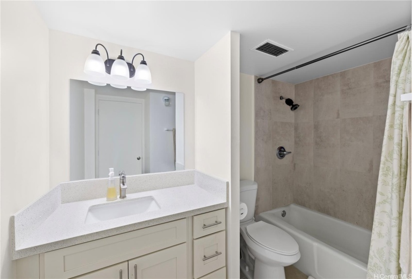 The remodeled hallway bath with tiled surrounds and tub