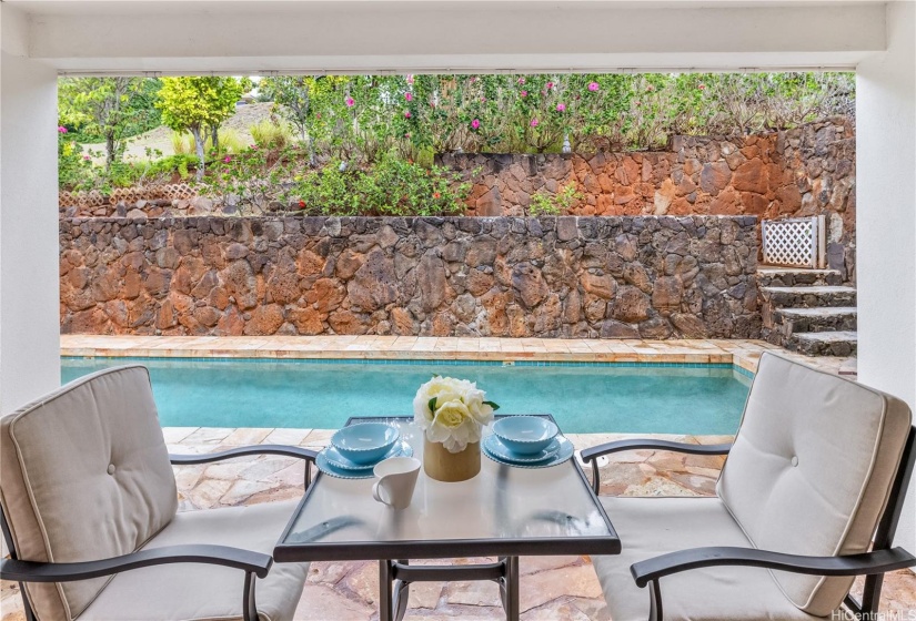 Relax under the covered lanai in the back yard with the lap pool and refreshing greenery.