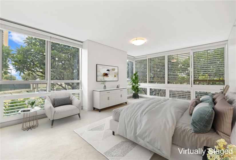 Primary bedroom facing east with large windows and treetop view