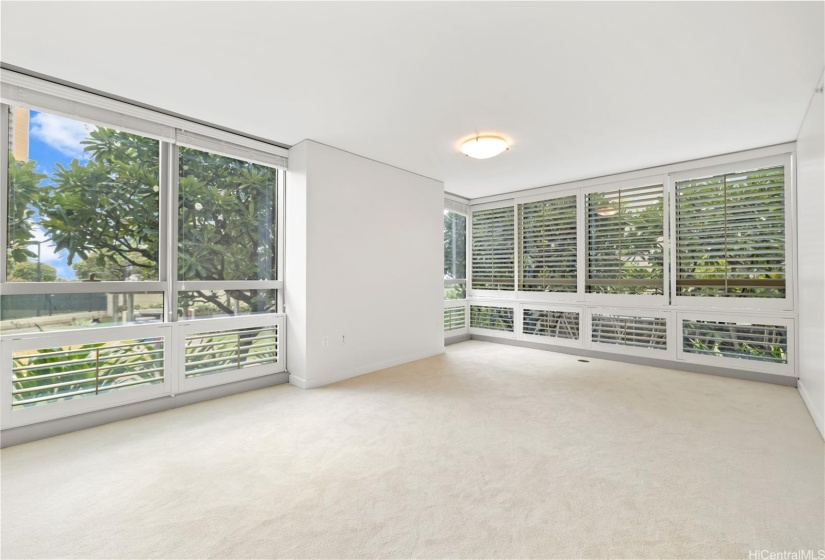 Primary bedroom facing east with large windows and treetop view