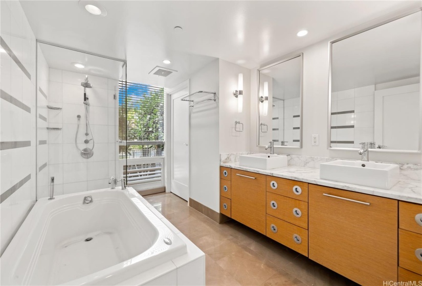 Primary bath with double sink vanity, shower & tub combination, and a walk in closet