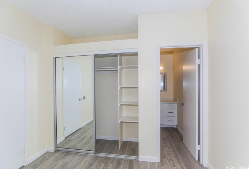 Another view of the Primary Bedroom with Mirror Closet Doors/Shelving in closet & door leading to full bathroom