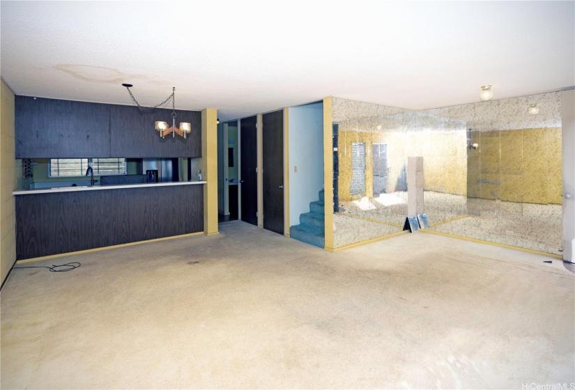 Looking across the living room toward the stairs, downstairs bathroom & kitchen (on the left).