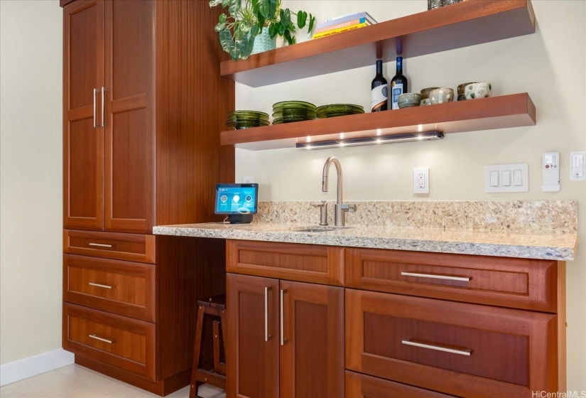 The bar area includes a sink, custom made floating shelves, space for a wine refrigerator and extra cabinetry.