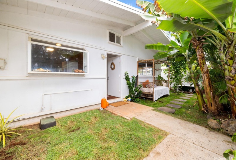 The charming tropical setting entrance features beautiful landscaping and an inviting outdoor bed lounge.