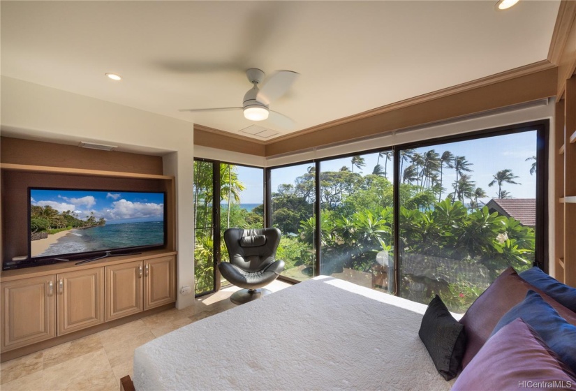 Floor to ceiling windows capture the views, palms, and light in one of the lower floor bedrooms.