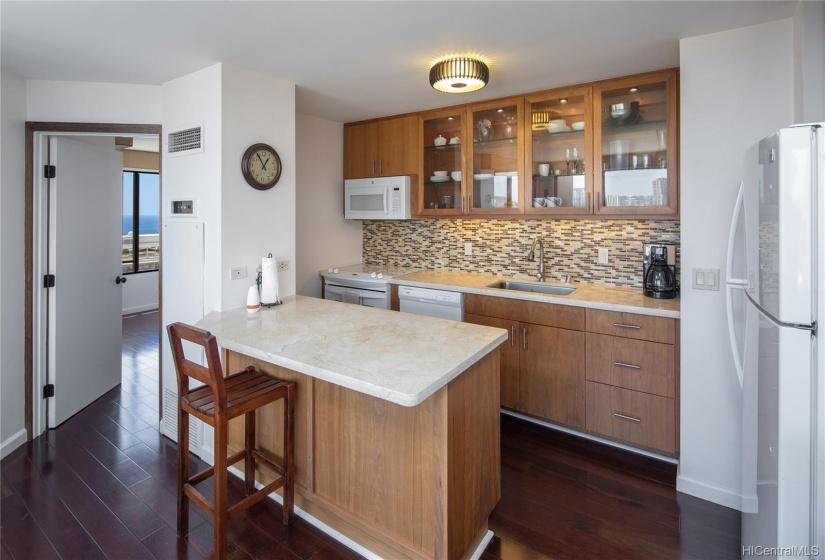 new kitchen cabinets with glass cabinet doors, tile backsplash, and counter tops.